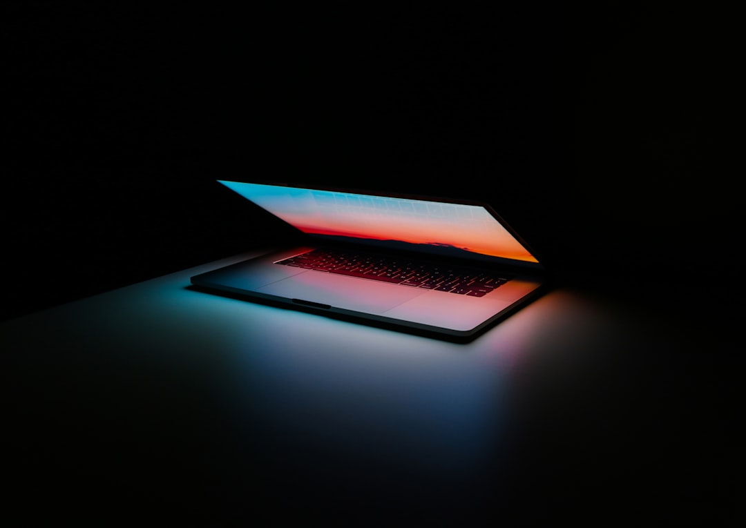 A laptop illuminated in dark surroundings with a colorful screen