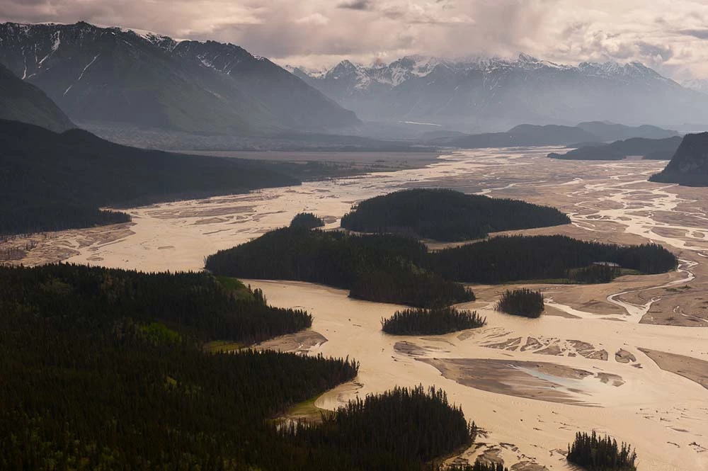 Aerial view of a winding river through mountainous terrain with forested areas